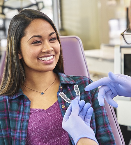 A woman smiling while a orthodontist shows her clear aligners