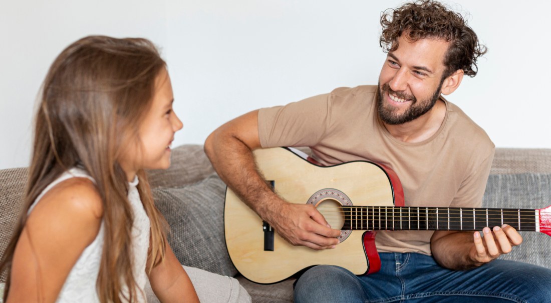 A man playing a guitar for a young girl